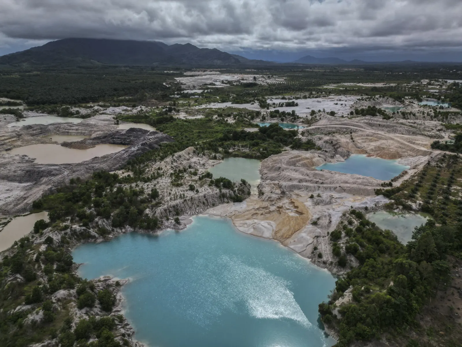 Aerial view of a Bangka Belitung landscape stripped by tin mining, pitted with turquoise flooded pits